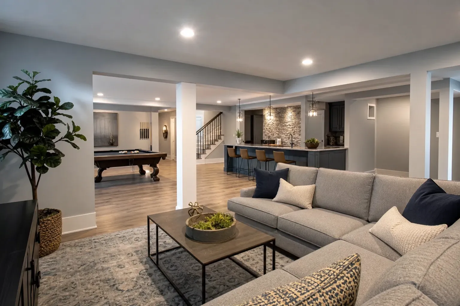 Finished basement with a sectional sofa, coffee table, pool table, wet bar, and staircase under recessed lighting.