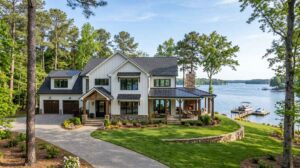 Newly built two-story modern-farmhouse custom home with white board-and-batten siding, stone water table, and covered lake-side porch on a wooded Lake Norman waterfront lot in Mooresville, NC